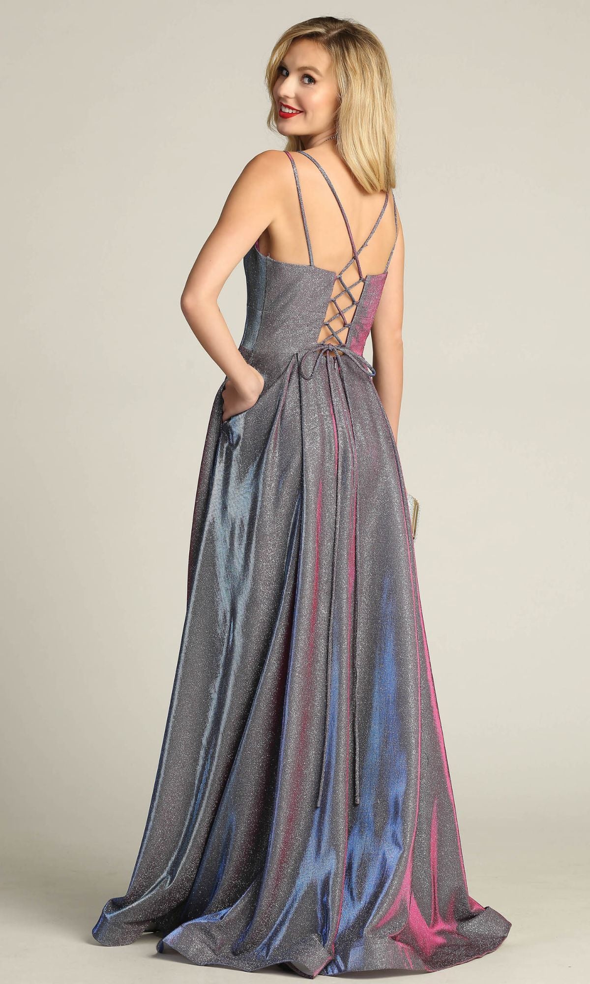 A woman models the Lace-Up Back Long Metallic A-Line Prom Dress 4022, featuring thin straps and a lace-up corset back, as she stands against a plain background looking over her shoulder.